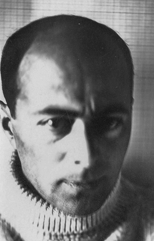 Black and white self portrait photograph of Russian Constructivism artist - El Lissitzky taken in 1914. Picture shows a dark-haired man looking straight in the direction of the camera